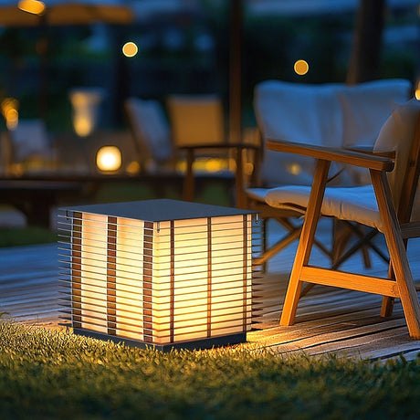 The cube lit on a deck beside timber chairs and a low garden table