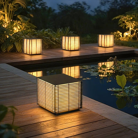 Two louvered cubes lit on a timber deck beside a pool at nightfall