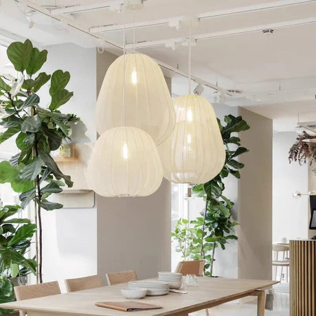Fabric lanterns lit above a wooden dining table with plants behind