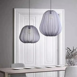 Two gray fabric lanterns hung at different heights in a pale room