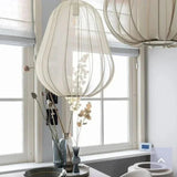 Lantern ceiling light in ivory fabric over a wire frame beside a window