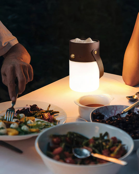 Lantern table lamp lit in the middle of a table set with bowls of food