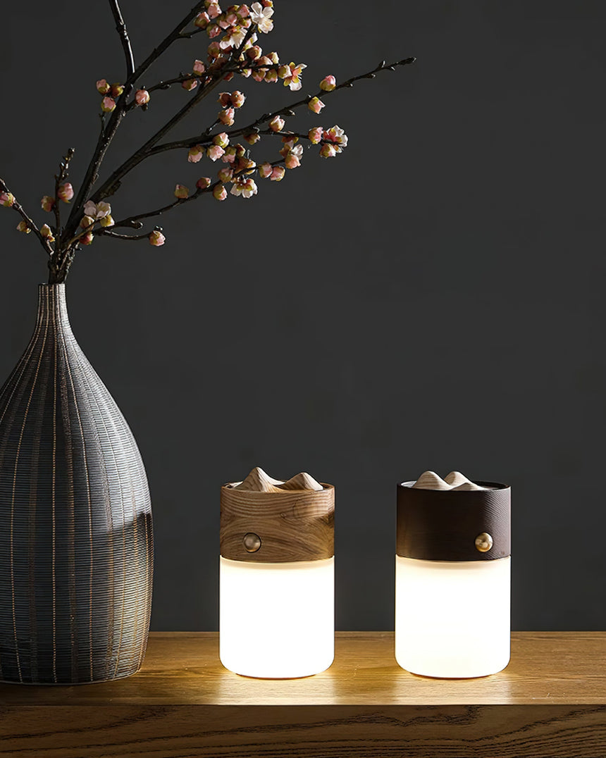 Two lantern table lamps lit on a shelf beside a tall patterned vase