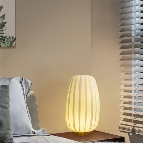 Pleated lantern lamp lit on a table beside a window with blinds