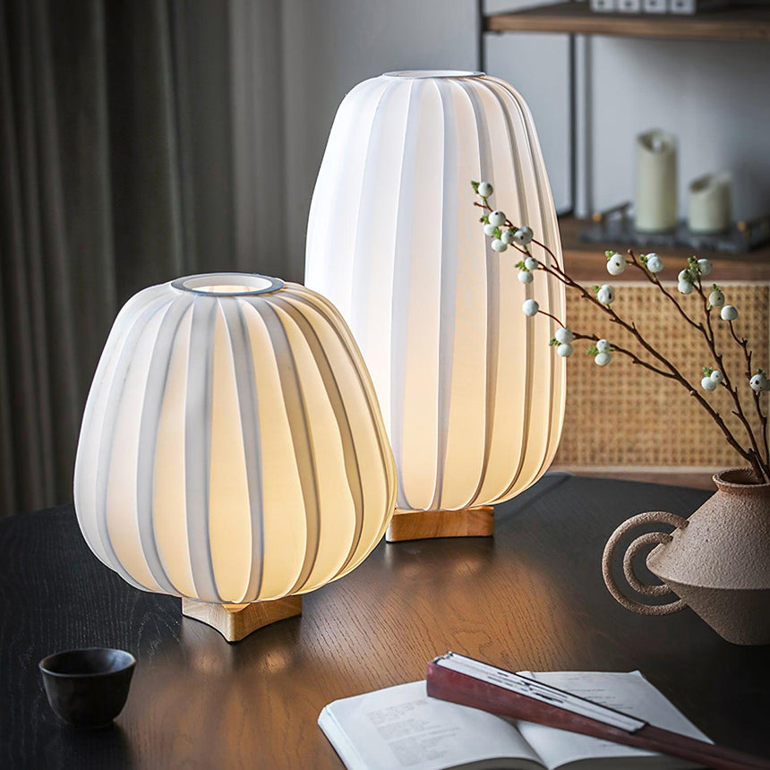 Two pleated lantern lamps lit on a dark desk beside a notebook