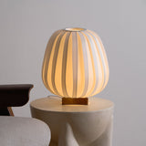 Pleated lantern lamp lit on a pale stone side table in a corner