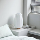 Pleated lantern lamp unlit on a white bedside table by a window