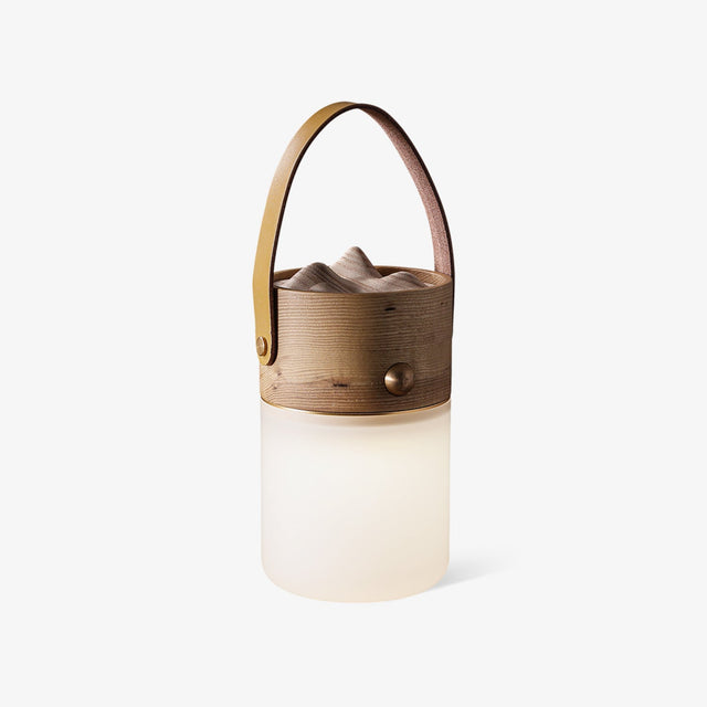 Lantern table lamp with a leather strap and a carved wood top, plain background