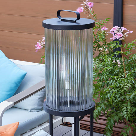 The tall lantern lit beside a lounger with flowering planting behind