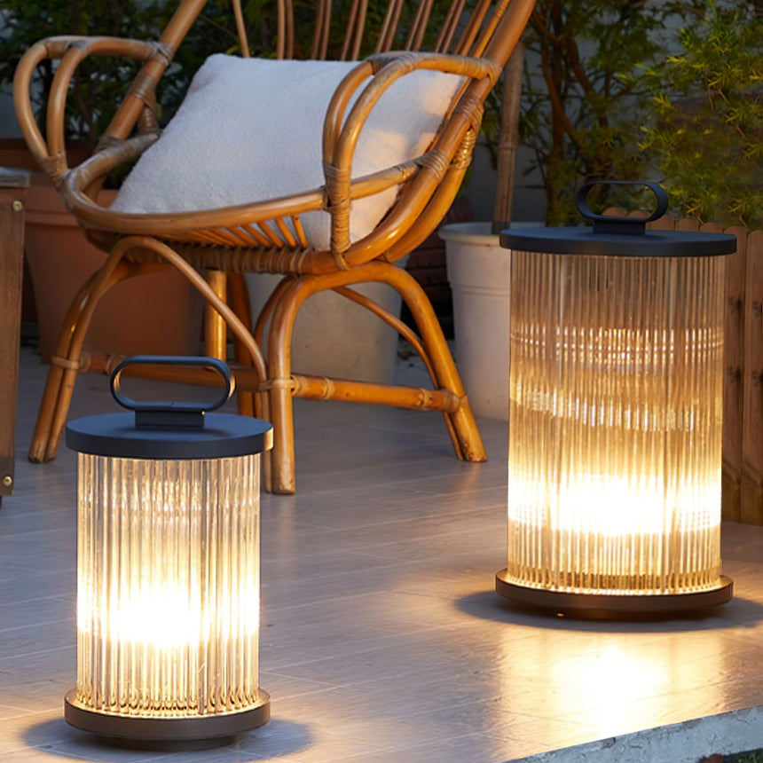 Two lanterns lit on a terrace beside rattan chairs with a cushion