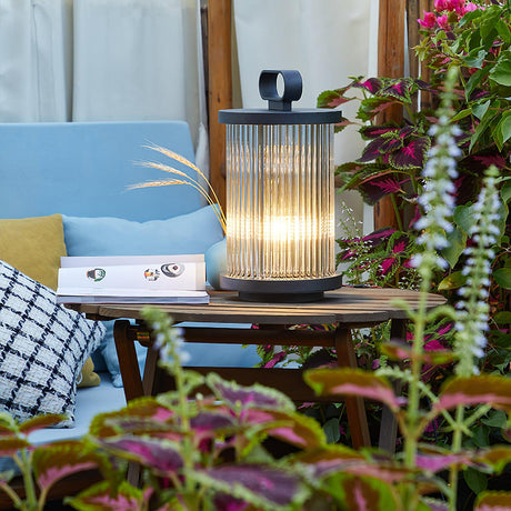 The lantern lit on a low table with planting and a cushion behind it