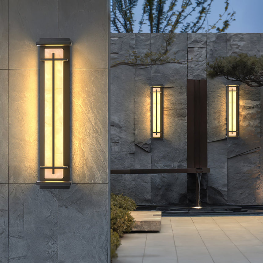 The lantern lit on slate cladding beside a water feature and planting
