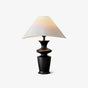 Large table lamp with a white coolie shade on a black turned wood base, plain background