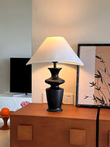 Large table lamp on a wooden chest in front of two framed bamboo prints