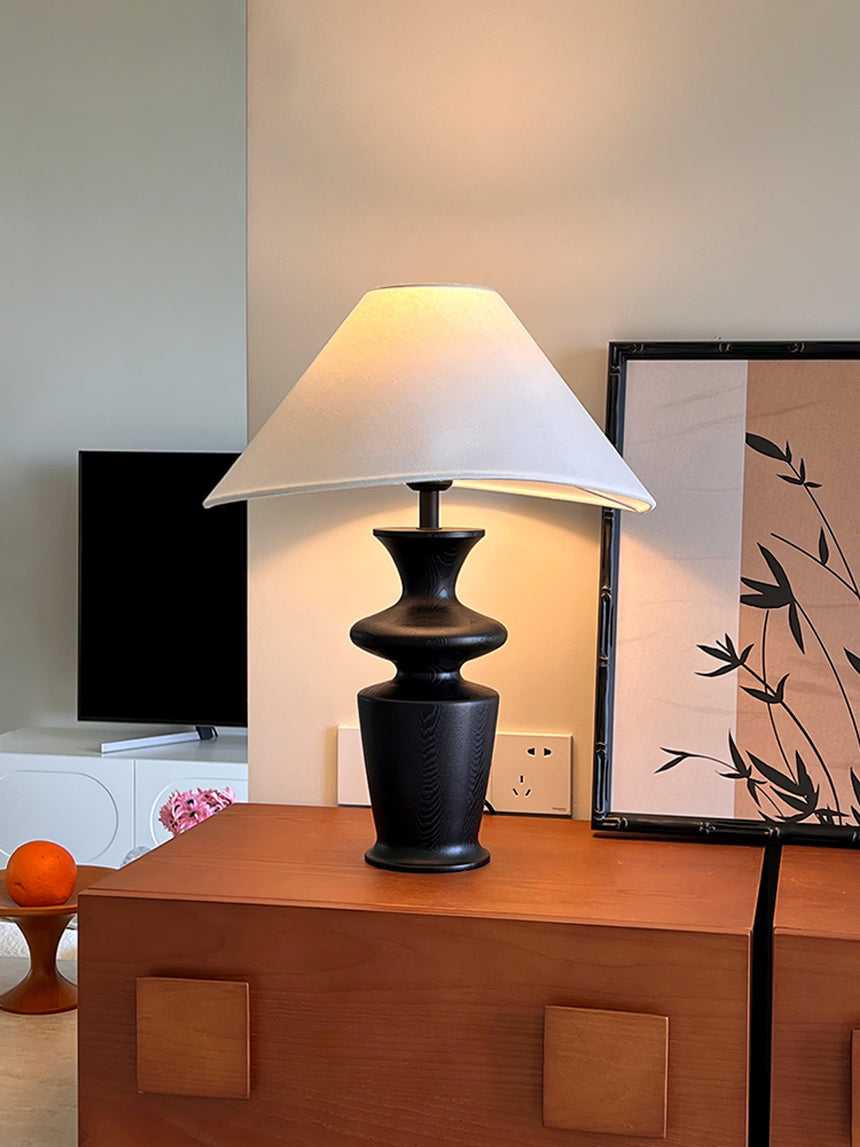 Large table lamp on a wooden chest in front of two framed bamboo prints