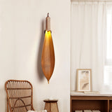 The leaf sconce above a rattan chair and a low table by a sheer curtain