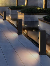 Lit along a terrace beside a raised planter with a stone coping