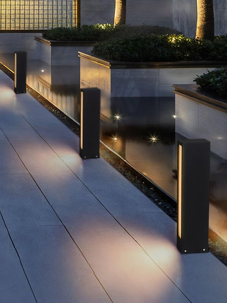 Lit along a terrace beside a raised planter with a stone coping