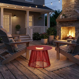 The table lit on a timber deck beside chairs and a stone fireplace