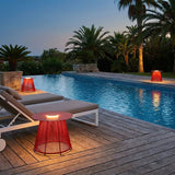 The table lit beside a pool with two loungers and palms behind them
