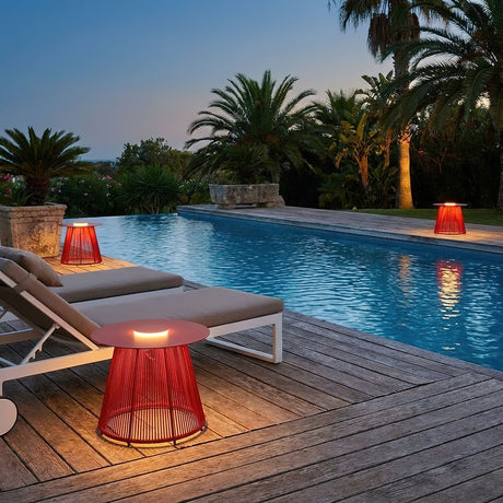The table lit beside a pool with two loungers and palms behind them