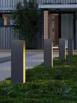 Two lit on a lawn near a lit entry with a slatted screen behind