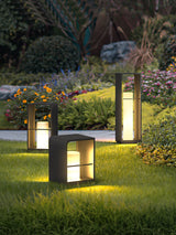 Two lit in a planted bed of grasses and flowers beside a lawn