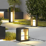 Three sizes lit together beside a paved walk with clipped planting