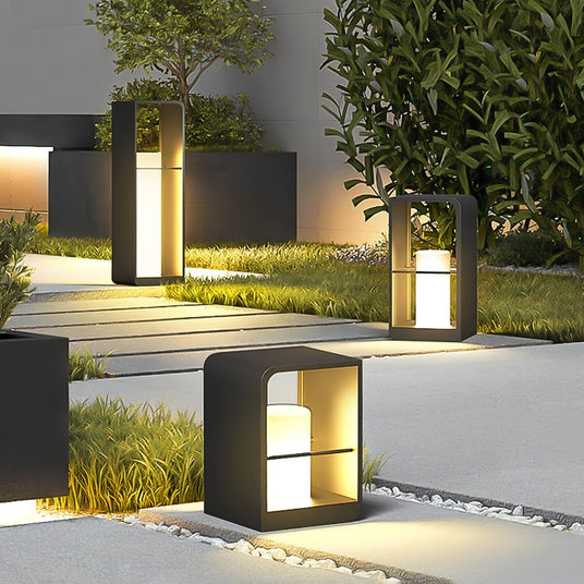 Three sizes lit together beside a paved walk with clipped planting