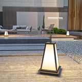 The lantern lit in a gravel courtyard with a lit house wall behind it