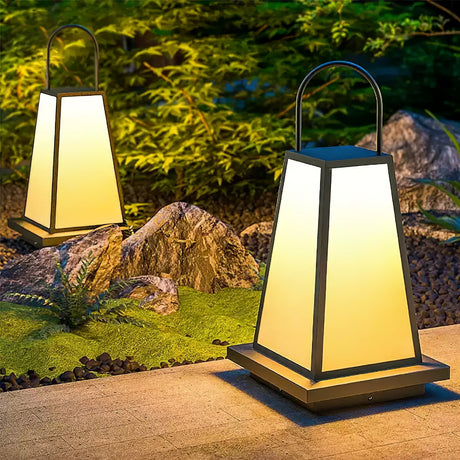Two lanterns lit on paving beside a rock garden with low planting