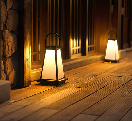 Two lanterns lit along a timber walkway beside a stone garden wall