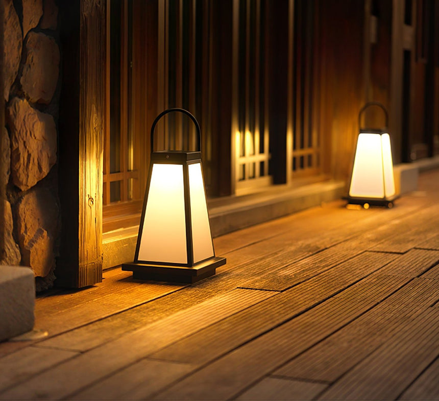Two lanterns lit along a timber walkway beside a stone garden wall