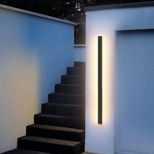A linear strip lit on a white wall beside a flight of outdoor concrete steps