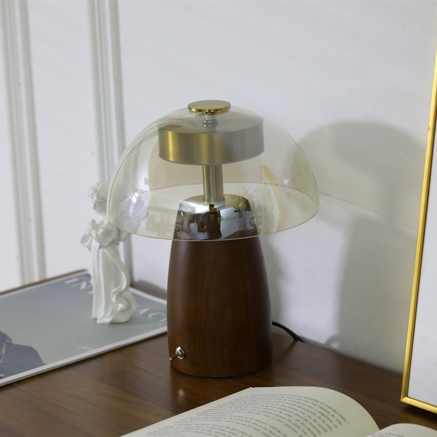 Clear dome LED table lamp lit in front of a framed print on the wall
