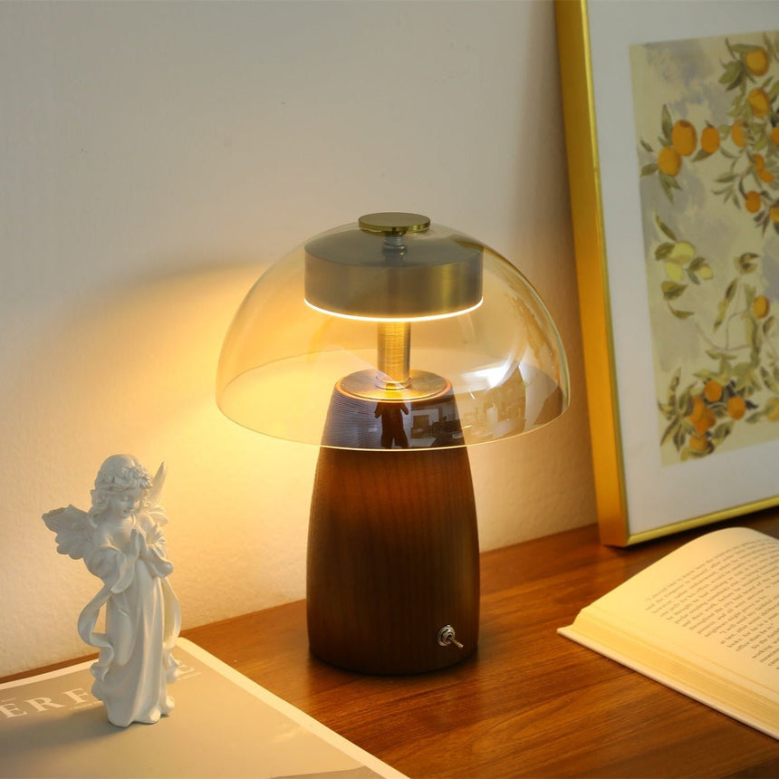 LED table lamp with the clear glass dome lit on a wooden desk