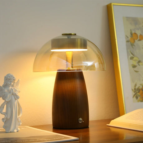 Clear glass dome version of the LED table lamp lit beside a figurine