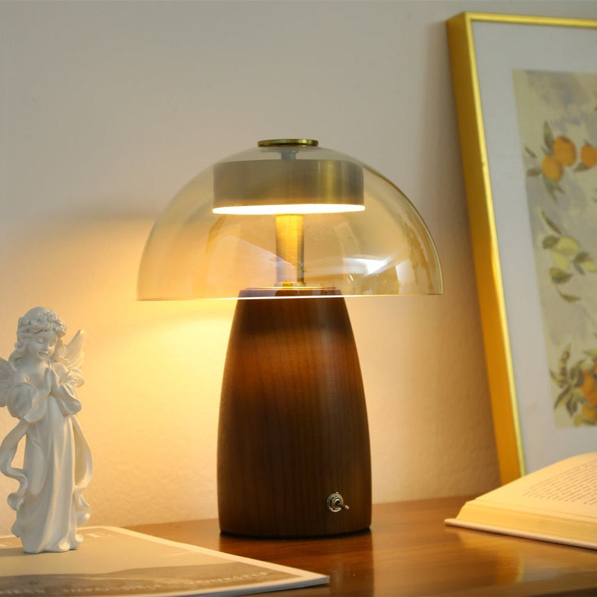 Clear glass dome version of the LED table lamp lit beside a figurine