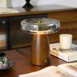 LED table lamp lit on a wooden table beside a white candle