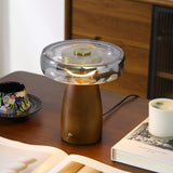 LED table lamp lit on a desk beside an open book and a cup
