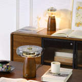 LED table lamp lit on a desk in a study with a wooden sideboard behind