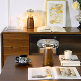 LED table lamp lit on a desk beside a vase of white flowers