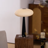LED table lamp lit on a plinth seen across a pale room