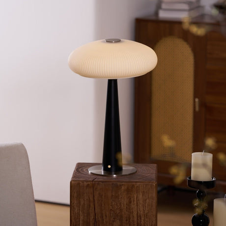 LED table lamp lit on a plinth seen across a pale room