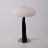 LED table lamp lit on a wooden plinth beside a lit pillar candle
