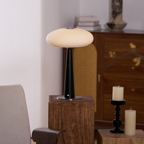 LED table lamp lit on a plinth beside an upholstered pale chair
