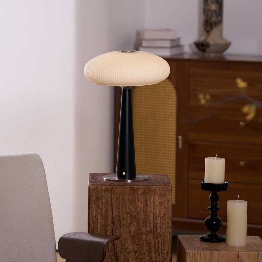 LED table lamp lit on a plinth beside an upholstered pale chair