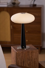 LED table lamp lit on a plinth beside the arm of a pale chair