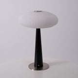LED table lamp lit on a wooden plinth beside a cane front cabinet
