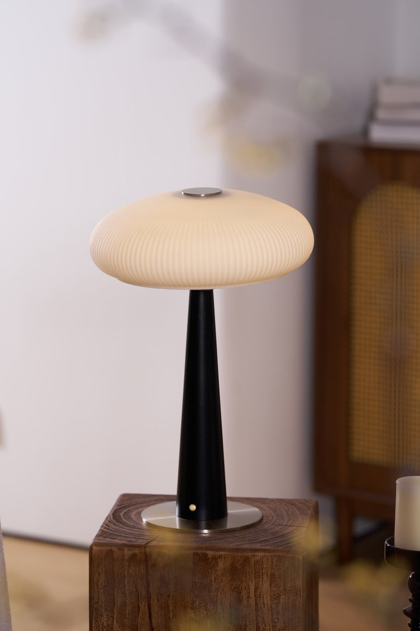 LED table lamp lit and seen from the side on a wooden plinth